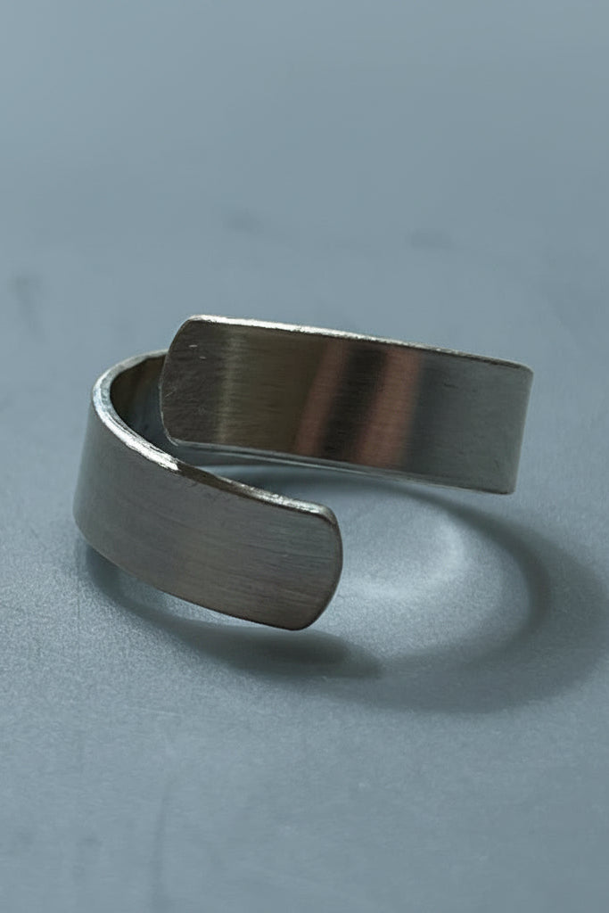 Silver color cuff ring on a gray surface.