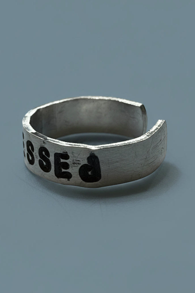 Silver color ring with engraved text on a gray surface.