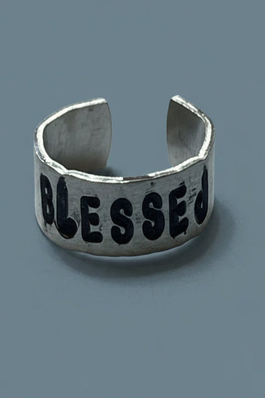 Silver color cugg ring with 'BLESSED' engraved by hand stamping on a gray background.