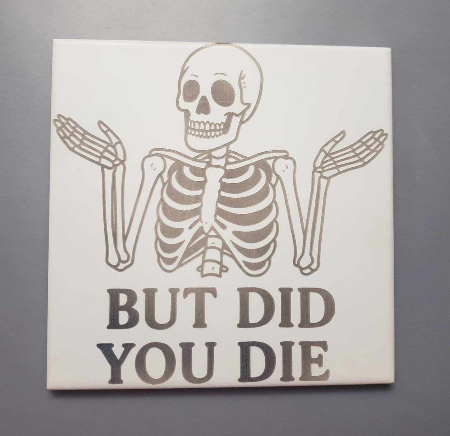 Ceramic tile measuring 6"x6" featuring a shrugging skeleton asking "but did you die" 