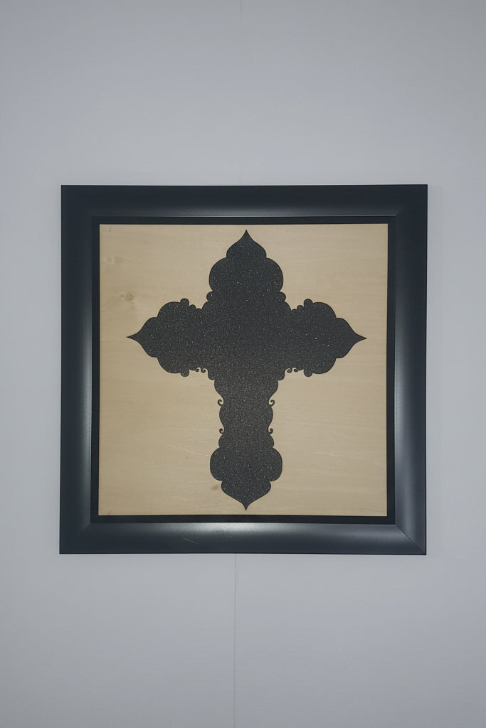 Decorative Shimmering Black Cross Silhouette behind wood and a black frame. 