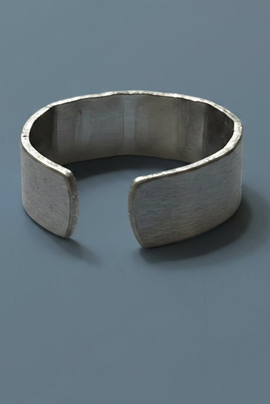 Silver colored open cuff ring on a gray background