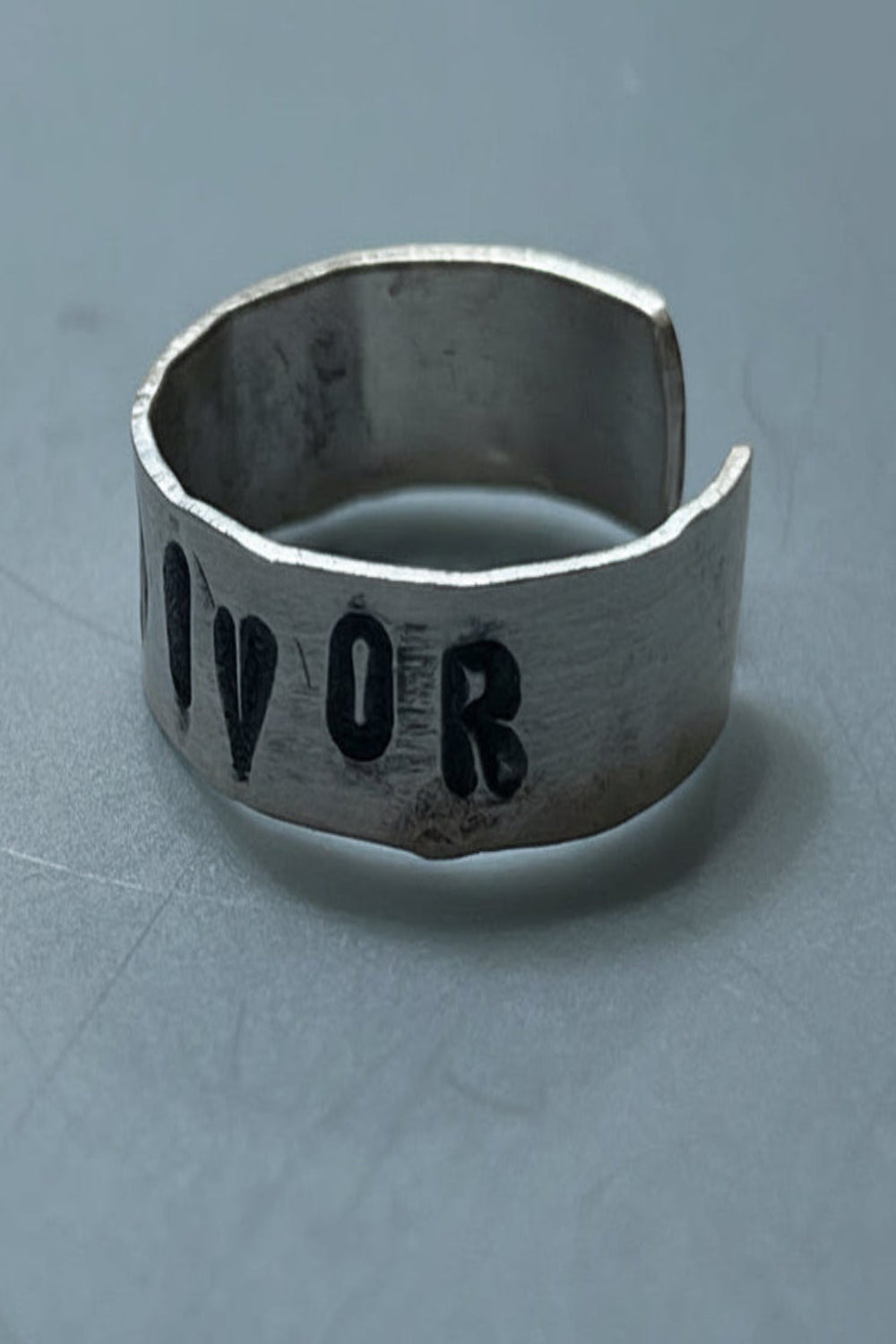 Silver colored ring with engraved text on a gray background