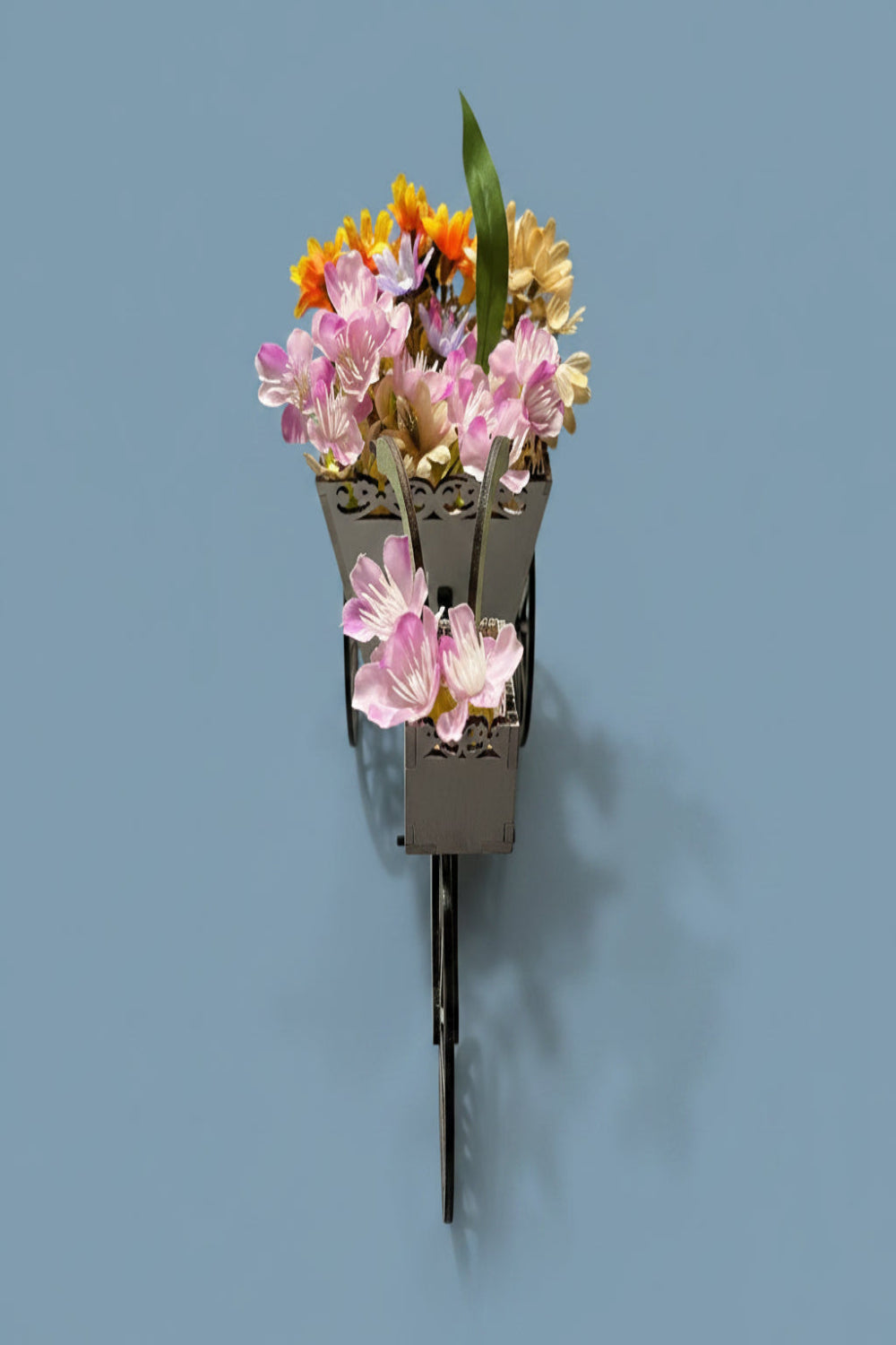 Front view of a small decorative flower arrangement in a wooden bicycle basket.