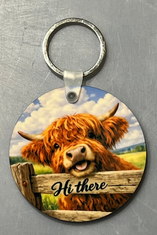 Adorable highland cow peeking over the fence saying hi there. 2 1/2"  round keychain