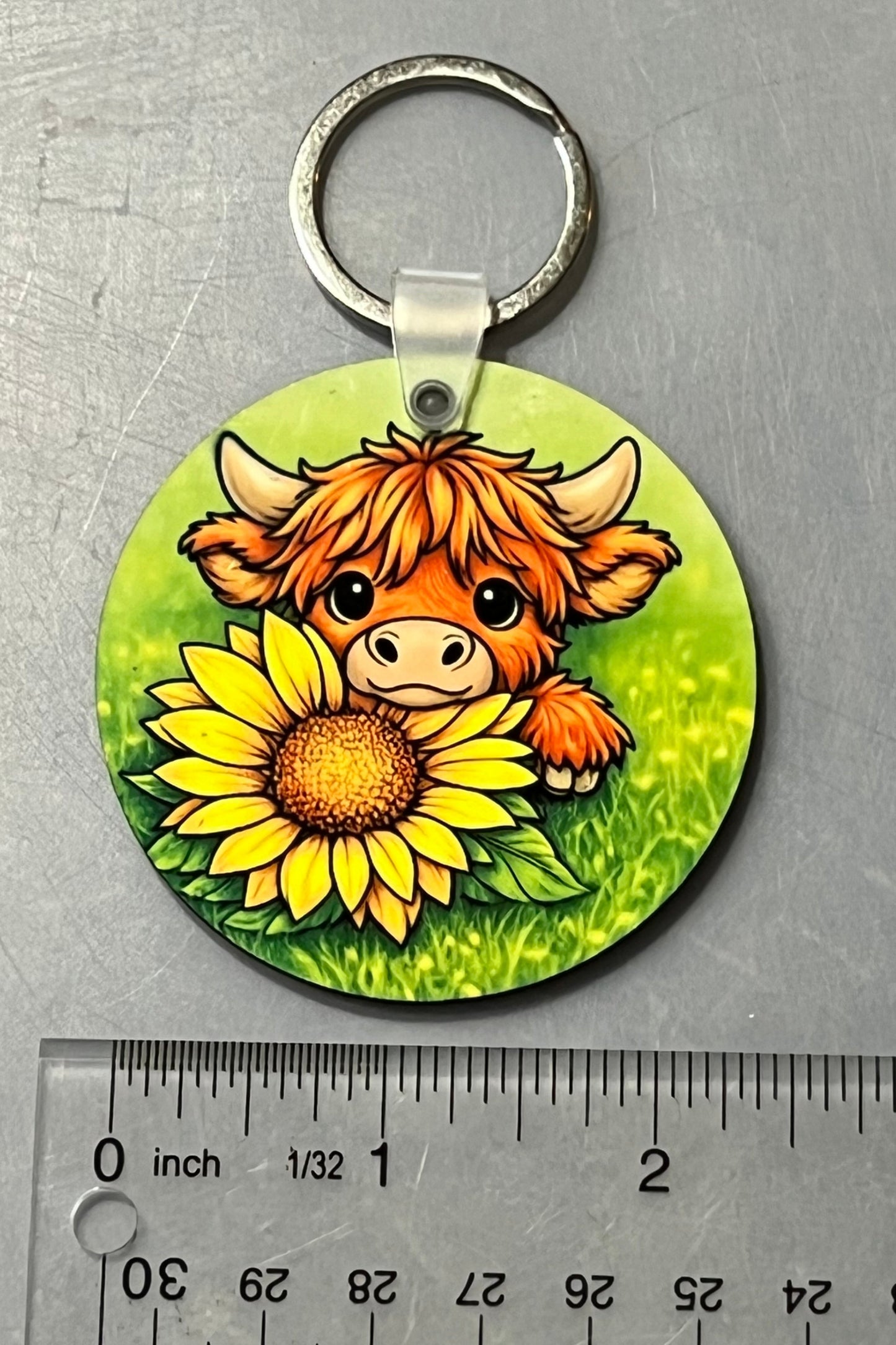 Highland Cow and Sunflower Keychain shown over a ruler for scale. 