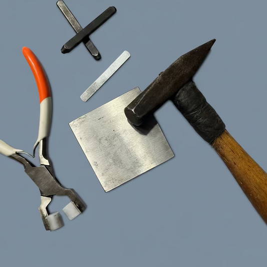 Set of tools used by Griffon for hand stamping includes a hammer, pliers, and metal pieces on a gray background