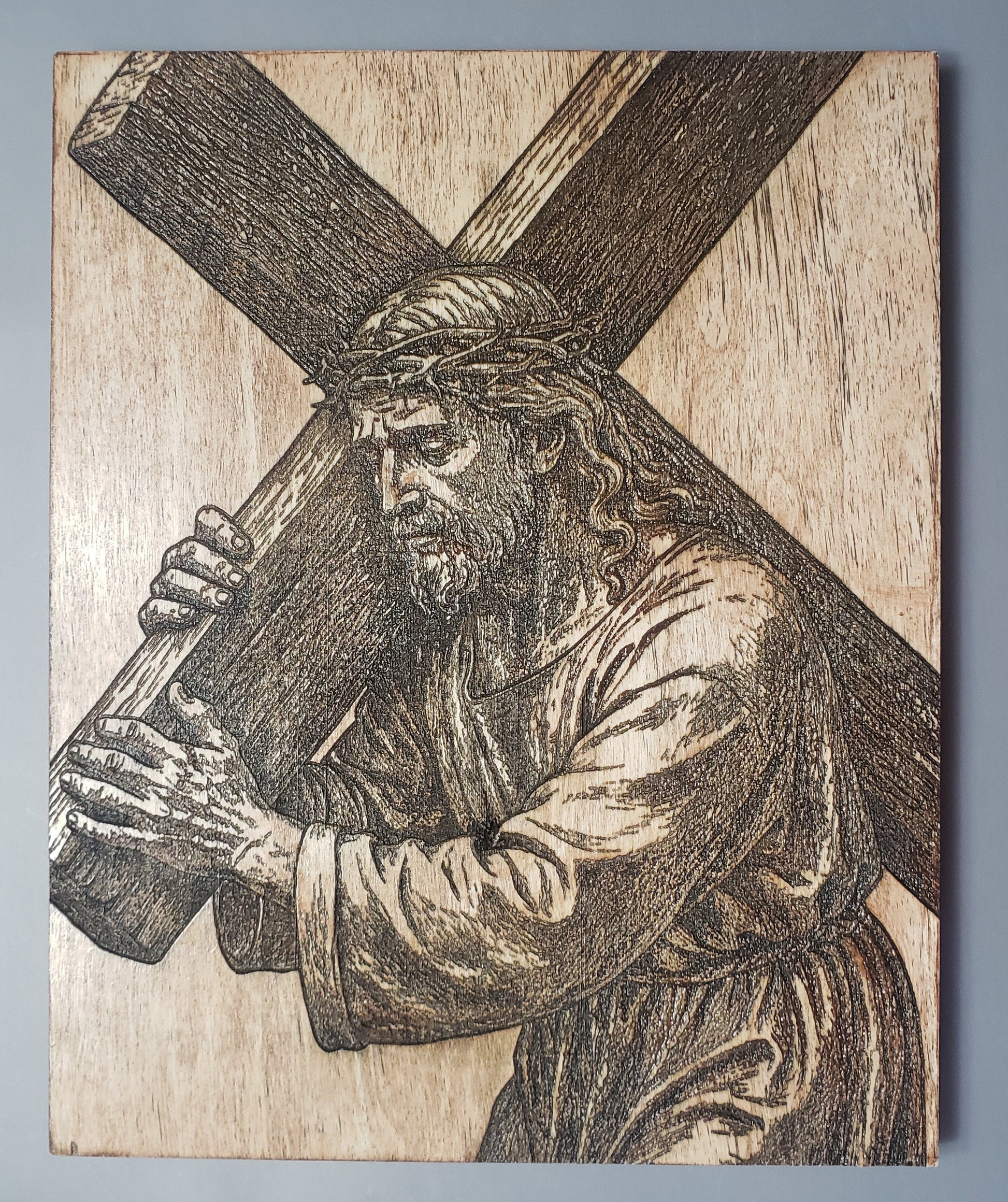 Wooden carving of Jesus carrying a cross on a plain background