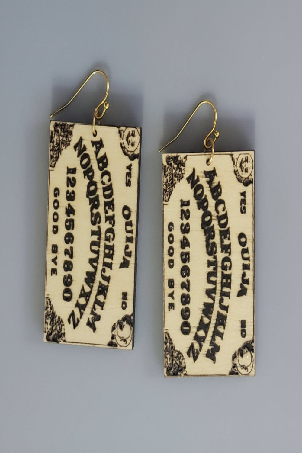 Ouija board-themed earrings etched in wood