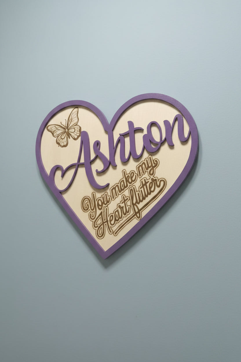 Heart-shaped personalized wooden plaque with 'You make my heart flutter' text and a butterfly burned into the wood.  The plaque is shown on a blue gray background.