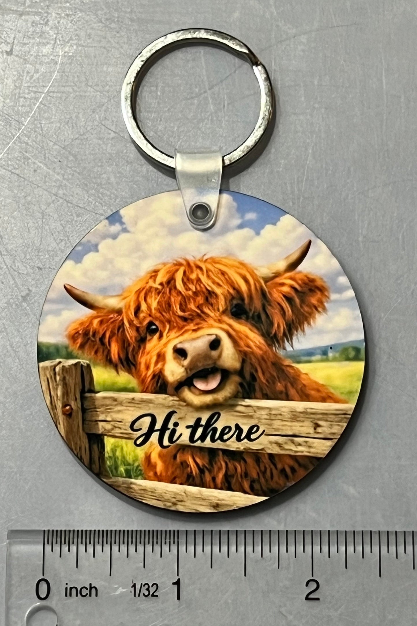 Adorable highland cow peeking over the fence saying hi there. 2 1/2"  round keychain