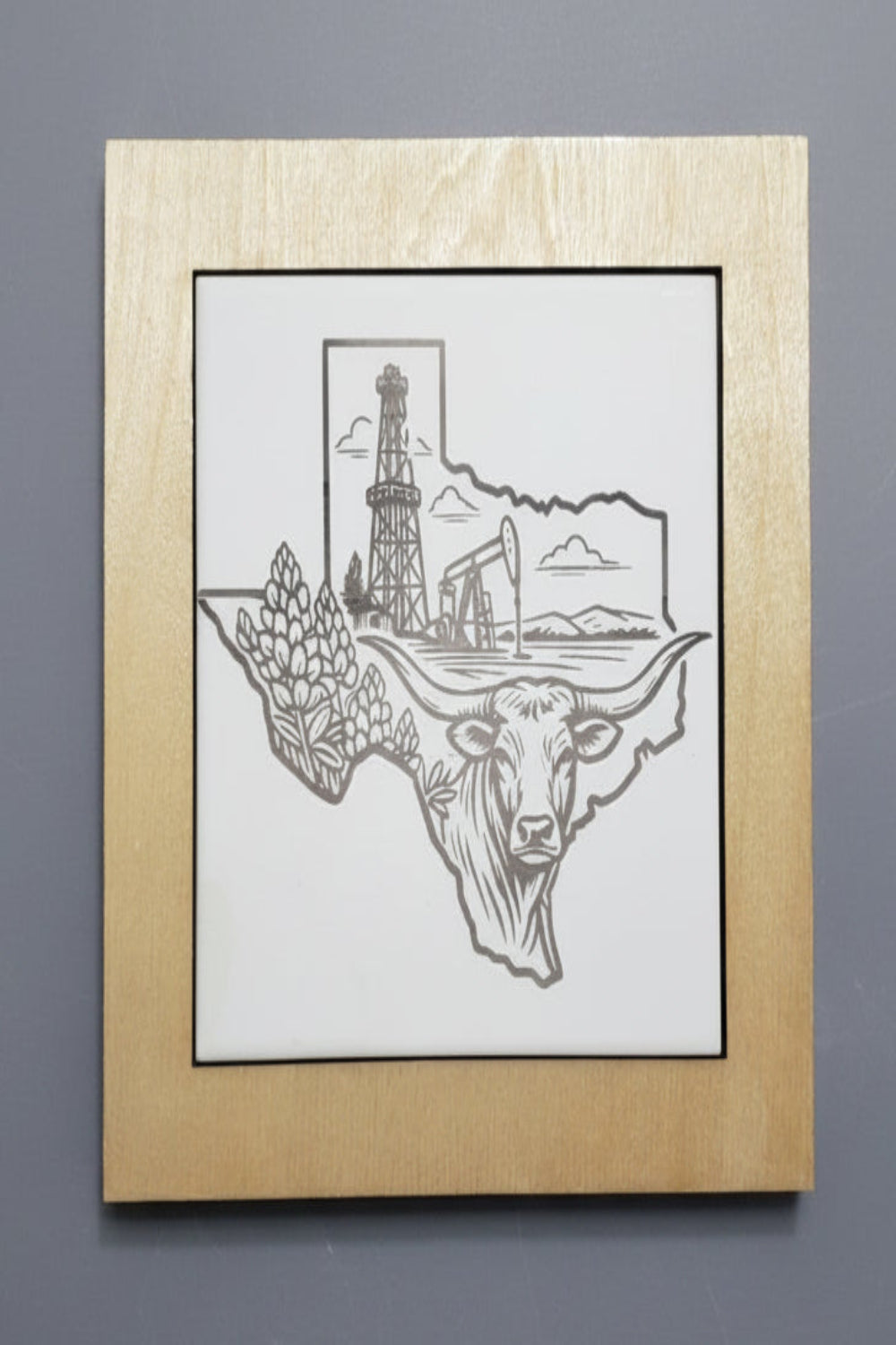 Wood framed trivet hot plate with ceramic tile etched with a longhorn bull with oil derrick and pumpjack illustrated in the shape of The State of Texas